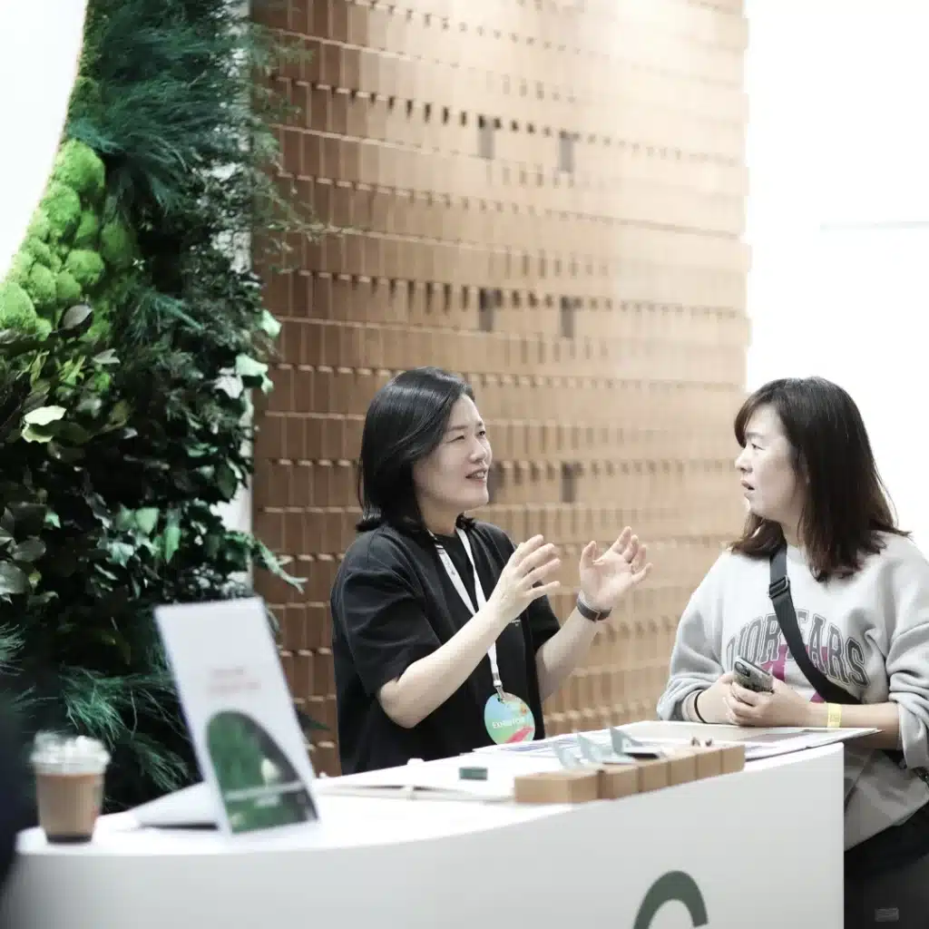 Two women discussing at an exhibition booth.