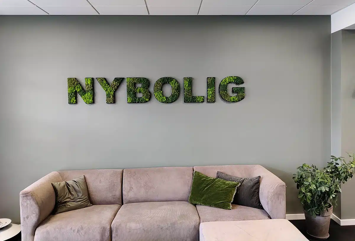 Modern office with sofa and plant wall art.