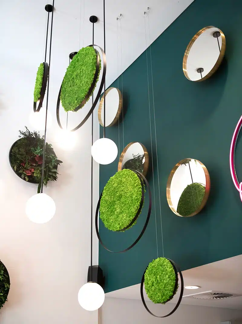 Modern vertical garden with circular mirrors and lights.