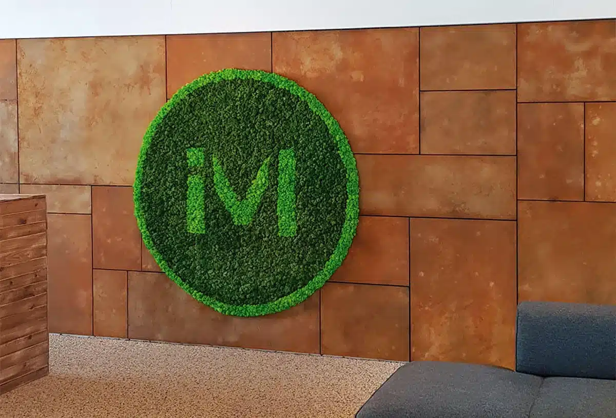 Grön väggkonst i mossa med "iM"-logotyp